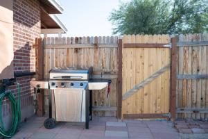 ein Grill vor einem Holzzaun in der Unterkunft Cali 2BR Getaway Firepit, Yard & Spring Charm in Tucson
