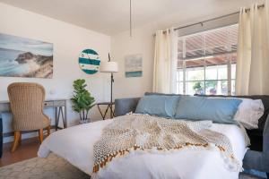 ein Schlafzimmer mit Bett, Schreibtisch und Fenster in der Unterkunft Cali 2BR Getaway Firepit, Yard & Spring Charm in Tucson