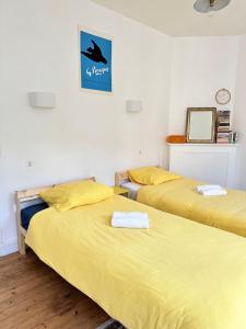 two beds in a room with yellow sheets at La Petite Escapade - Maison de pêcheur traditionnelle - Centre-ville in Fécamp