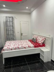 a bedroom with a white bed with red sheets and pillows at Studio Le Parisien in Pointe-Noire