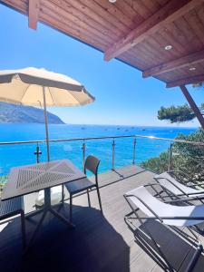 a deck with a table and chairs and an umbrella at Villaggio Smeraldo in Moneglia