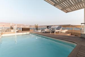 a large swimming pool on a deck with chairs at Queen Anne - Penthouse apartment with private pool in Eilat