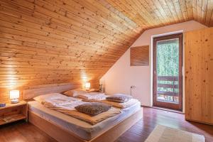 2 letti in una camera con soffitto in legno di Podhamer Wellness Vineyard Cottages a Ljutomer Altre 48 foto