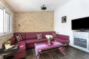 a living room with a purple couch and a tv at Paraíso Radazul in Radazul