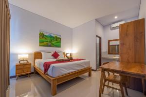 a bedroom with a bed and a table and a desk at Villa Raksa Canggu in Canggu