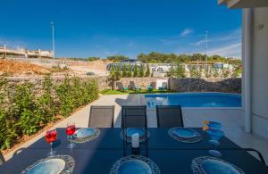 a table with wine glasses on a patio with a pool at Villa DIVINA with heated pool in Krk