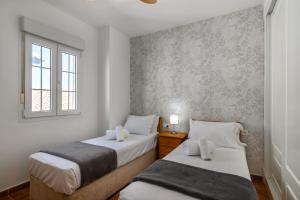 zwei Betten in einem kleinen Zimmer mit Fenster in der Unterkunft Marina IV Atico by Ĥ - Marina Isla Canela PMHIV30P30 in Punta del moral