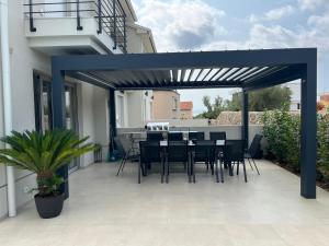 a blue pergola on a patio with a table and chairs at Villa DIVINA with heated pool in Krk