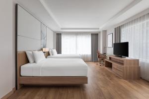 a white bedroom with a bed and a television at Courtyard by Marriott Bangkok in Bangkok