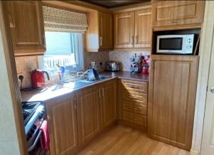 a kitchen with wooden cabinets and a sink and a microwave at Sea View in Port Seton