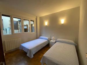a bedroom with two beds and two windows at Sego Apartments III in Segovia