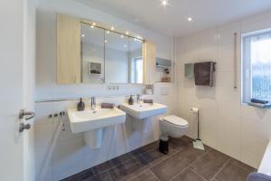 a white bathroom with two sinks and a toilet at Fewo Bodenseeoase in Wangen +11 photos