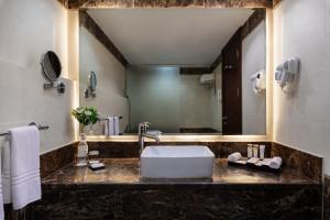 un bagno con un lavandino e un grande specchio di Warwick Hotel Jeddah a Gedda
