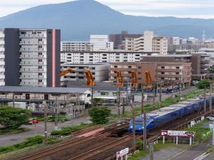 ein Zug auf Gleisen in einer Stadt mit Gebäuden in der Unterkunft Hotel Sun Valley Annex in Beppu