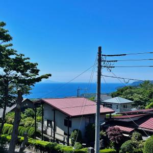 a house with a pink roof with the ocean in the background at I Love Izu in Futo