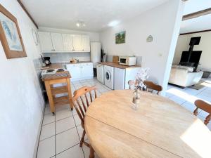 a kitchen and dining room with a wooden table at Rose Cottage with seasonal Swimming Pool in Le Mesnil-Gilbert