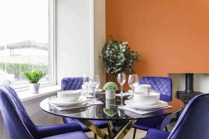 a dining room with a glass table and purple chairs at Braelochan Stay in Balloch