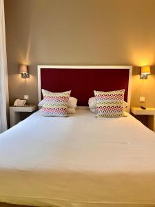 a bedroom with a large white bed with two pillows at Kyriad Paris 18 - Porte de Clignancourt - Montmartre in Paris