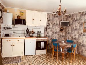 a kitchen with white cabinets and a table and chairs at Appartement MUSÉE Le JOUR-J in Ouistreham