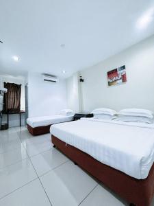 two beds in a room with white walls at Asia Green Hotel in Sungai Besar