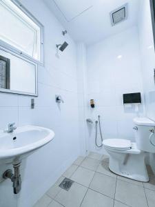 a white bathroom with a toilet and a sink at Asia Green Hotel in Sungai Besar
