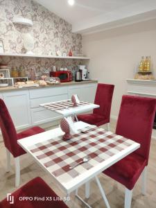 Una cocina con una mesa de tablero de ajedrez y sillas rojas. en Il Melograno chic&nature, en Santa Maria La Carità
