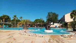 a pool at a resort with a statue in the middle at Le paradis du sud in Sérignan