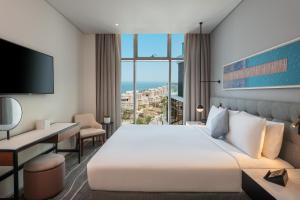 Una habitación de hotel con una cama grande y un escritorio. en Th8 Palm Dubai Beach Resort, Vignette Collection by IHG, en Dubái