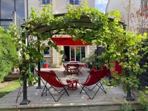 a patio with a table and chairs under an umbrella at Maison terrasse et jardin à proximité de Paris in LʼHay-les-Roses