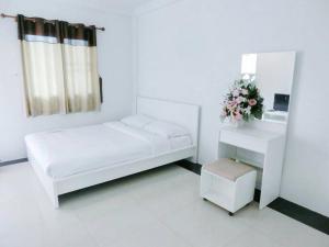 a white bedroom with a bed and a mirror at Pichayapa Place in Ban Pa Sang (1)