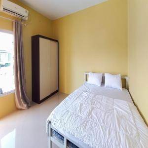 une chambre avec un grand lit blanc avec une fenêtre dans l'établissement FARAH Homestay Syariah Mitra RedDoorz, à Pekanbaru