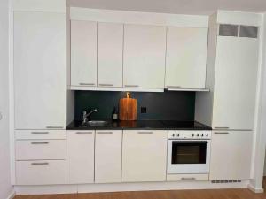 a white kitchen with white cabinets and a sink at Tjuvholmen - balcony with seaview & 2 bedrooms in Oslo +16 photos