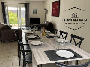 a dining room with a table with plates and wine glasses at Le gîte des pélus in Rochecorbon