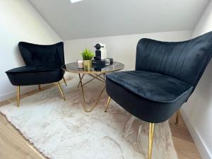 two black chairs and a table in a room at Spa, nature et vous in Ennevelin