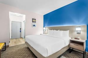 uma grande cama branca num quarto com uma parede azul em Comfort Suites Denver North - Westminster em Westminster