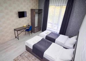 une chambre avec deux lits, un bureau et une télévision dans l'établissement Minguzar Hotel, à Yakkasaray