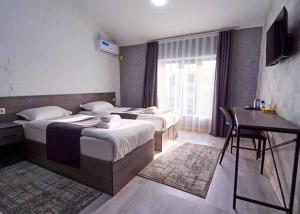 une chambre avec deux lits et un bureau et une fenêtre dans l'établissement Minguzar Hotel, à Yakkasaray
