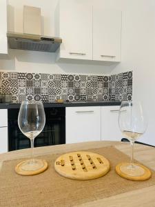 Dos copas de vino y una tabla de cortar en la encimera de la cocina. en Jungle Love Room de l Hermitage, en Tournon-sur-Rhône