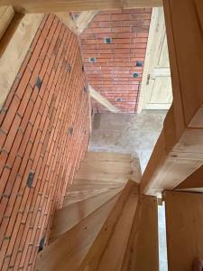 a wooden staircase in a room with a brick wall at Cabana lac Apa Stefania in Medieşu Aurit