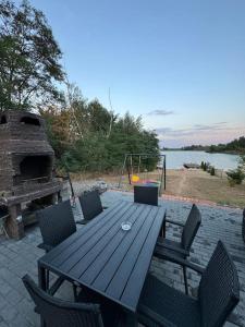 a wooden picnic table with chairs and a fireplace at Cabana lac Apa Stefania in Medieşu Aurit