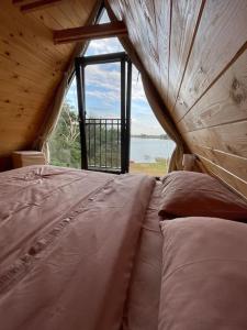 a large bed in a room with a large window at Cabana lac Apa Stefania in Medieşu Aurit