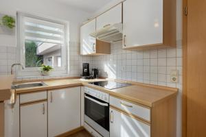 een keuken met witte kasten, een gootsteen en een raam bij Ferienwohnung Herzlicht in Titisee-Neustadt