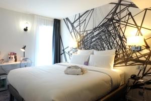 - une chambre avec un grand lit blanc et un mur noir et blanc dans l'établissement Mercure Paris Malakoff Parc des Expositions, à Malakoff