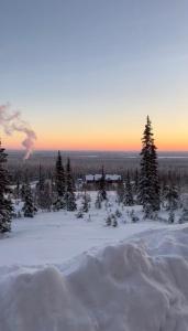 a view of a snowy field with trees and smoke at Arctic Hill Apartment Ylläs in Ylläs