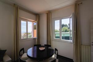 a dining room with a table and two windows at "Lomellina Bay" 10 minuti a piedi dal mare in Varazze