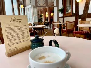 マールブルク・アン・デア・ラーンにあるVetters romantisches Gästezimmer in der Marburger Oberstadtのメニューの横のテーブルに置かれたコーヒーカップ