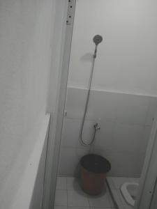 a bathroom with a shower with a toilet and a bucket at Rumah Putih Edi in Sengkol