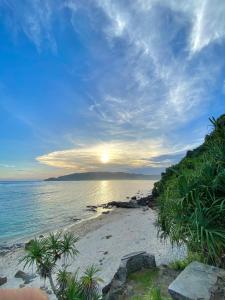a beach with the sun setting over the ocean at Rumah Putih Edi in Sengkol