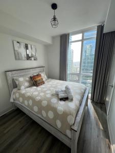 a bedroom with a large bed with a large window at Prestigious 2-Bdrm Condo - across from Scotiabank Arena in Toronto