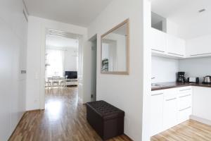 a white kitchen with a black stool in a room at Casa Nostra - Sonnige Wohnung direkt am Augarten in Vienna